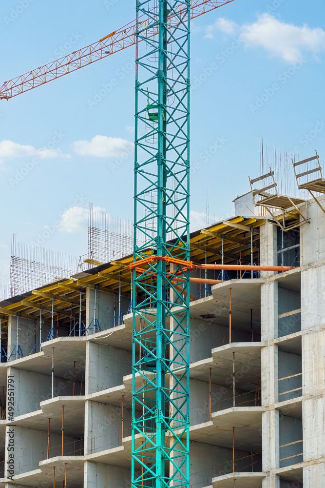 construction of a modern high-rise building, the creation of a concrete frame, building materials and a construction crane