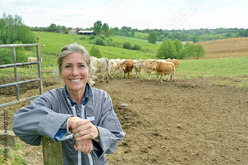 Smiling woman breeder in field, livestock in background photo