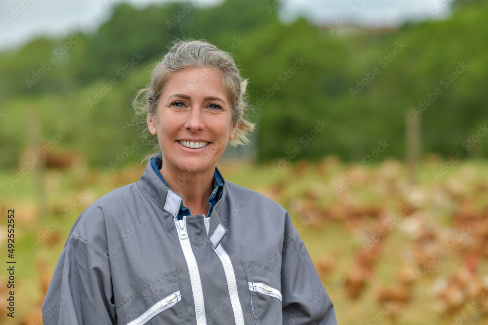 Smiling breeder woman standing in farm, herns in background Smiling breeder woman standing in farm, herns in background