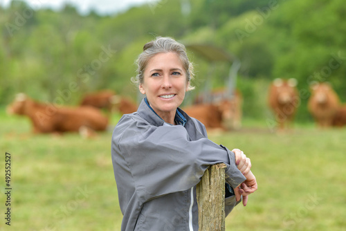 Smiling breeder woman standing in farm, livestock in background