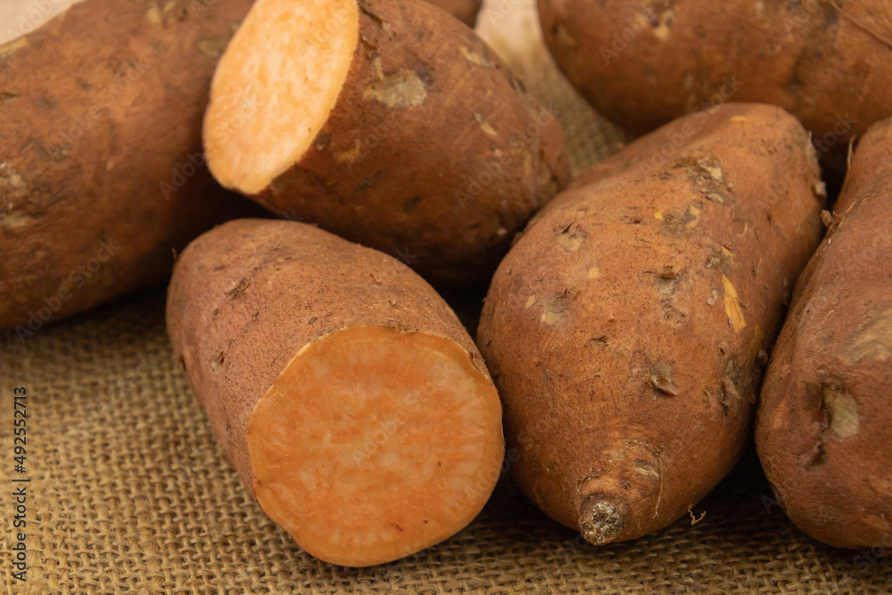 close up of whole and cut sweet potato on burlap close up of whole and cut sweet potato on burlap