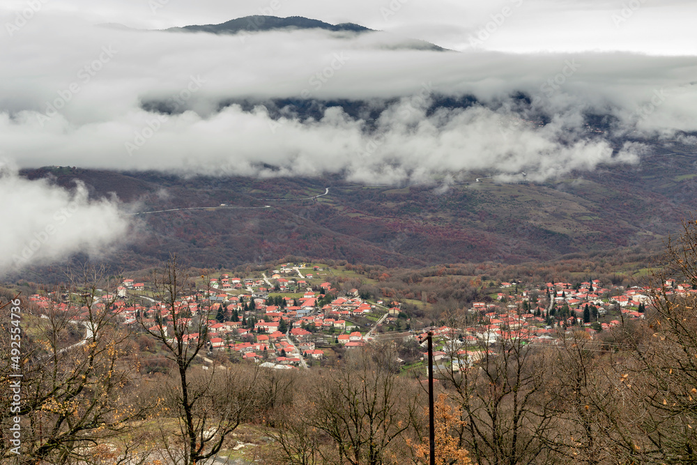 View of the village (Greece, Epirus) and snow-covered mountains in a winter on a cloudy day View of the village (Greece, Epirus) and snow-covered mountains in a winter on a cloudy day