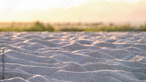 Close up of clean yellow sand surface covering seaside beach illuminated with evening light. Travel and vacations concept
