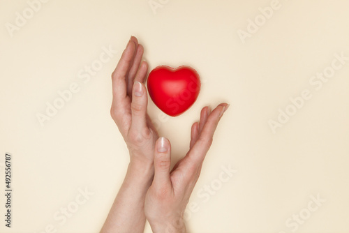 Fototapeta Naklejka Na Ścianę i Meble -  Health, medicine and charity concept - close up of female hands with small red heart