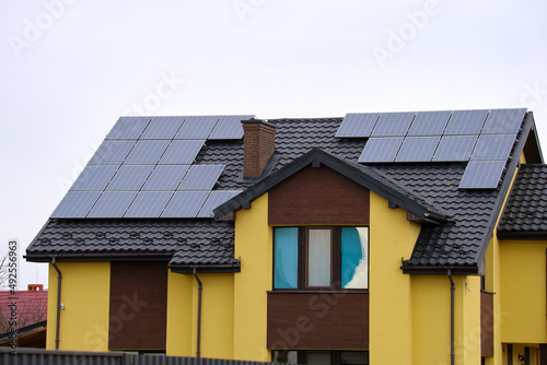 Private home roof covered with solar photovoltaic panels for generating of clean ecological electric energy in suburban rural town area. Concept of autonomous house