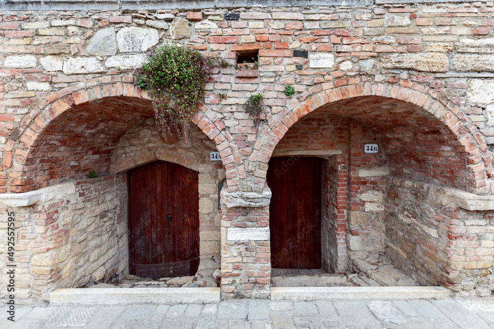 Arched entrance with thick medieval walls to a building in the Bagno Vignoni. Tuscany, Italy