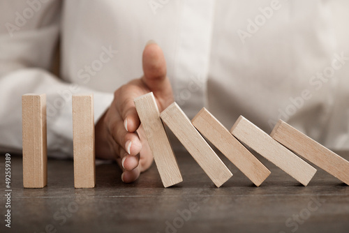 hand stops falling wooden domino blocks, risk insurance concept, crisis manager, domino principle photo