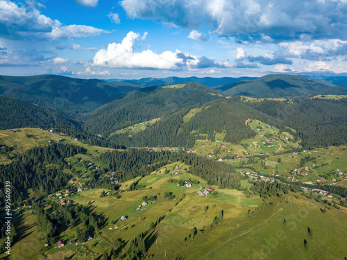 Green mountains of Ukrainian Carpathians in summer. Sunny day, rare clouds. Aerial drone view.