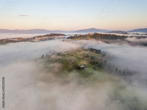 Mountain settlement in the Ukrainian Carpathians in the morning mist. Aerial drone view.