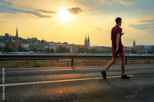 Young man in sportswear walking on the street at sunset © Yury Kirillov