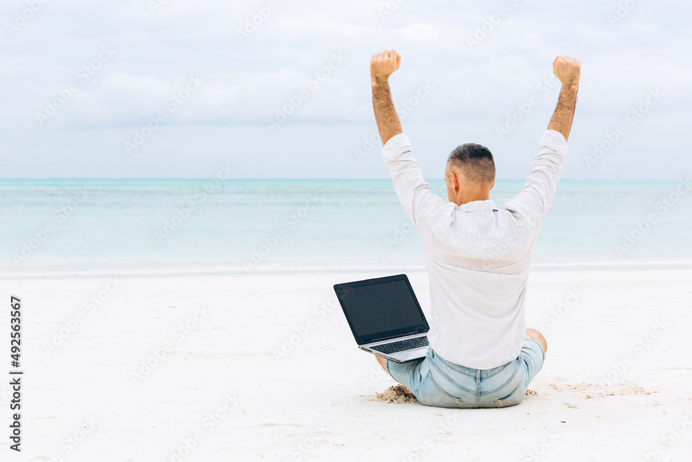 Successful Young man using laptop computer on the beach. Relaxation Vacation Working Outdoors Beach Concept