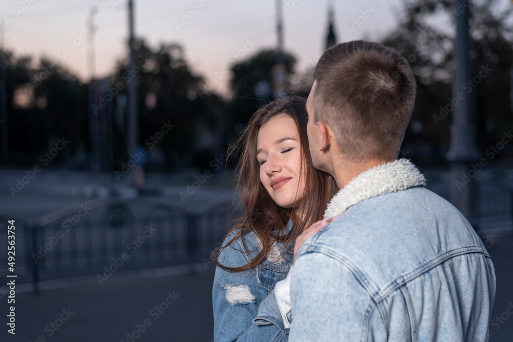 Fototapeta premium Young beautiful couple in love hugs on evening city background