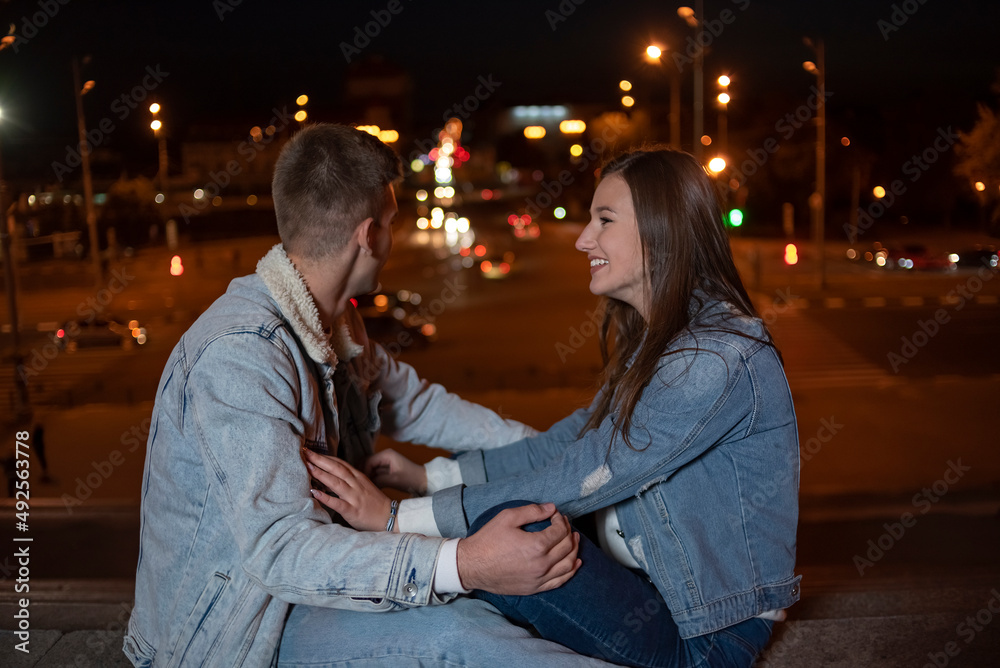 Young caucasian couple on background of the evening city. Date in the city.