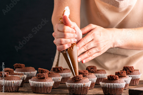 Foto Pastry-cook hand prepare chocolate cupcakes