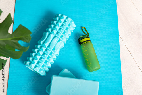 Top view of sports equipment on the yoga mat top view. Massage roller, yoga bricks and bottle of water. photo