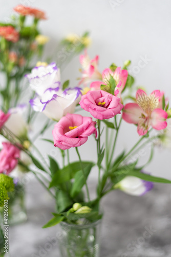 Fototapeta Naklejka Na Ścianę i Meble -  Colorful flowers composition over grey background with copy space. Fresh cut flowers for decoration home. Flower arrangement in a vase for home. Women's Day and spring time flower background