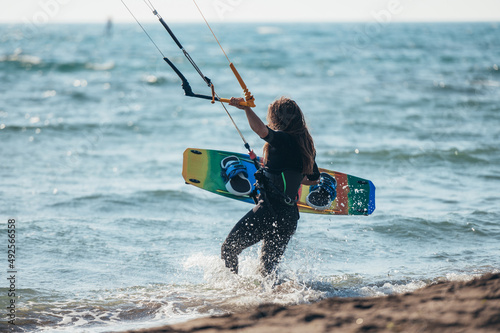Wall Mural Woman holding kiteboard and going into the water