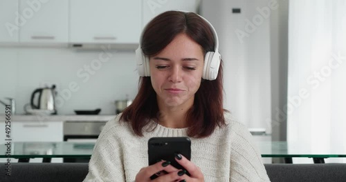 beautiful young girl in headphone sitting at her workplace at home when thinking about answer when chatting with friends on social media
