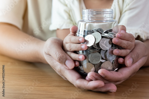 Adult and kid hands holding a coins jar savings and donation concept
