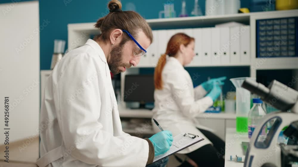 Man and woman scientists working at laboratory Man and woman scientists working at laboratory