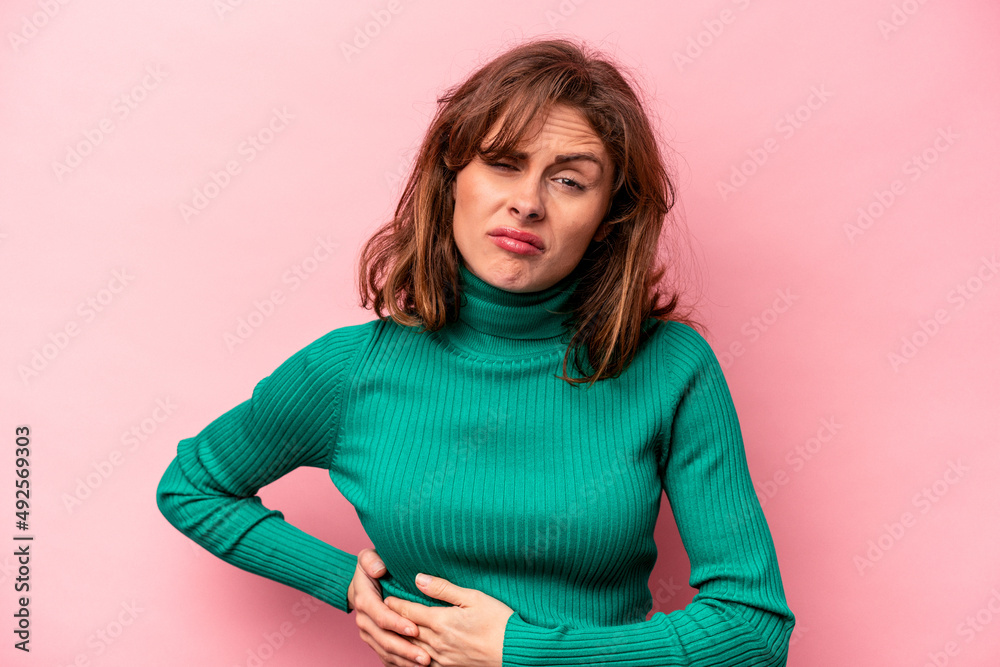 Fototapeta premium Young caucasian woman isolated on pink background having a liver pain, stomach ache.