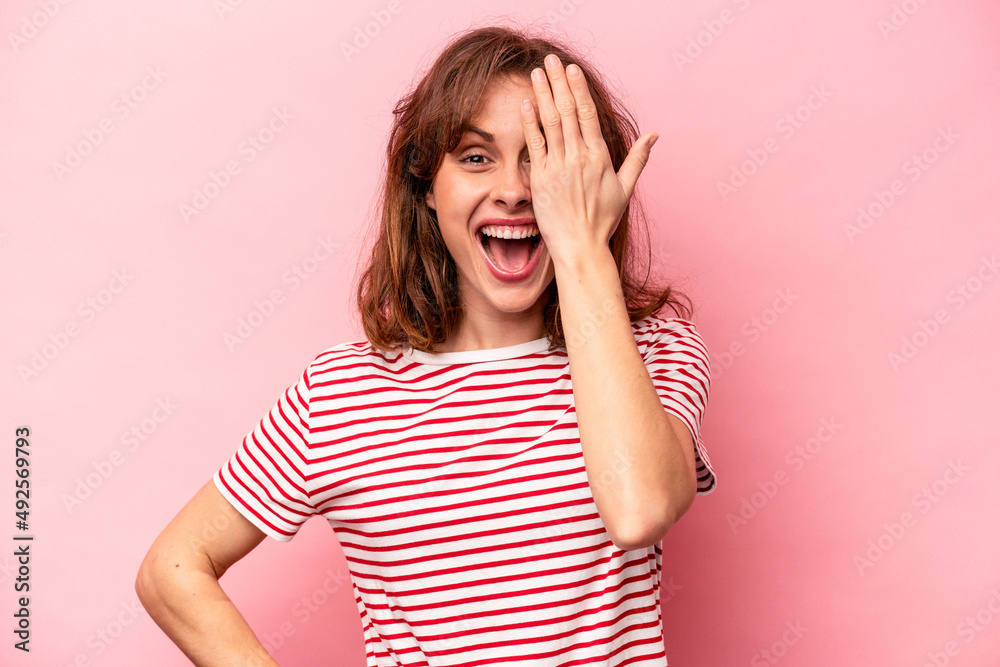 Young caucasian woman isolated on pink background having fun covering half of face with palm. Young caucasian woman isolated on pink background having fun covering half of face with palm.