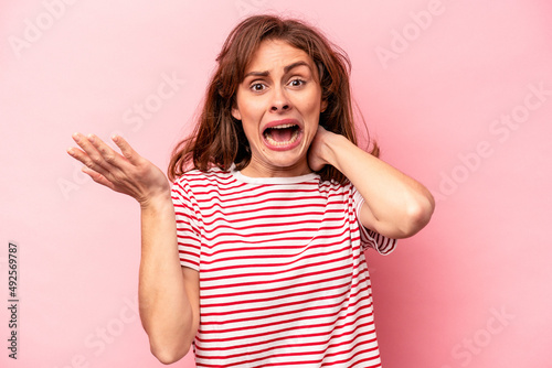 Young caucasian woman isolated on pink background screaming with rage.