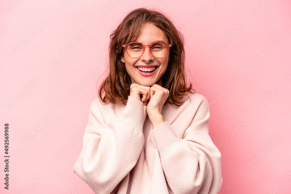 Young caucasian woman isolated on pink background keeps hands under chin, is looking happily aside. Young caucasian woman isolated on pink background keeps hands under chin, is looking happily aside.
