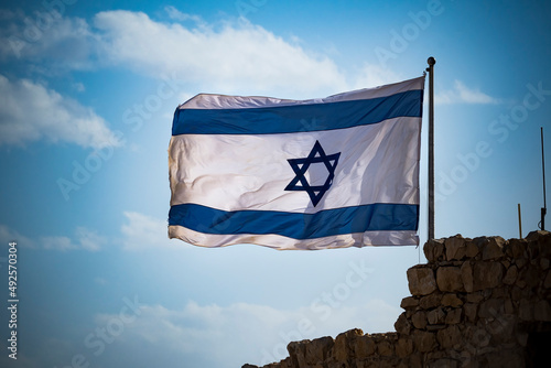 Flag of Israel fluttering in strong wing against cloudy sky