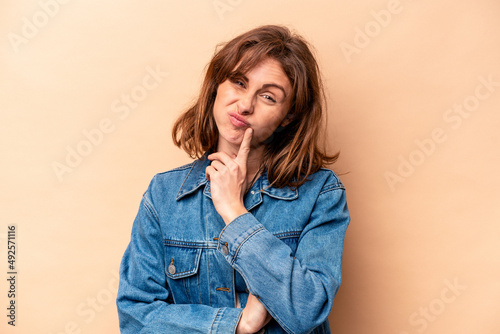 Young caucasian woman isolated on beige background unhappy looking in camera with sarcastic expression.