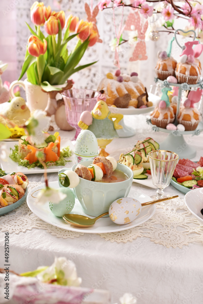 Easter table with salads and white borscht with quail egg and sausage skewer