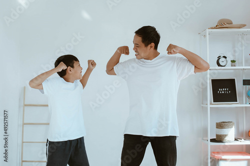 Asian young father and son in white tshirt are playing together at home showing cheerful and atrractive expression photo