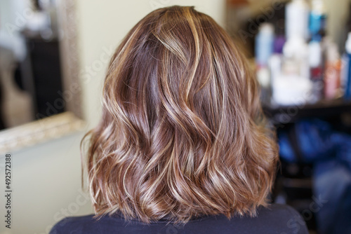 brunette woman with shiny brown curly hair back view in salon