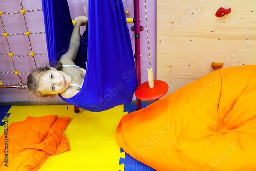 an autistic girl is treated at the center by a psychologist, exercises in a hammock help the brain, balance, cerebellum
