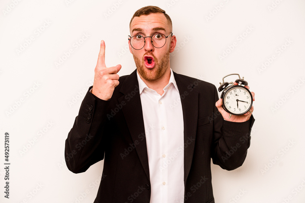 Young business caucasian man holding alarm clock isolated on white background having some great idea, concept of creativity. Young business caucasian man holding alarm clock isolated on white background having some great idea, concept of creativity.