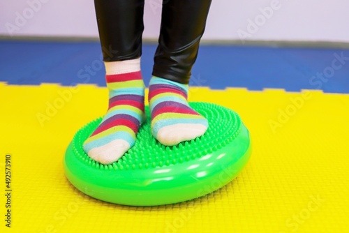 a little girl walks with her feet on a studded ball in the children's center as if on a track