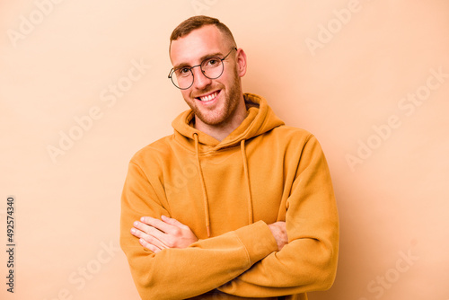 Young caucasian man isolated on beige background happy, smiling and cheerful.