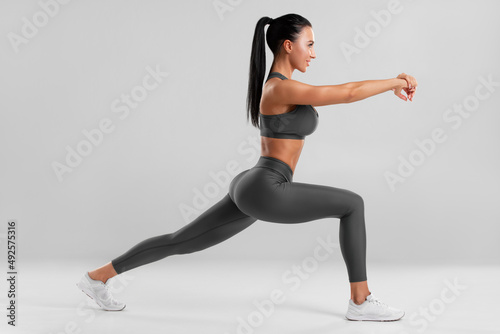 Fototapeta Naklejka Na Ścianę i Meble -  Fitness woman doing lunges exercises for leg muscle training. Active girl doing front forward one leg step lunge exercise