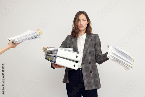Принти на полотні Stressed female worker and business woman holding a pile of paperwork while getting more work to do