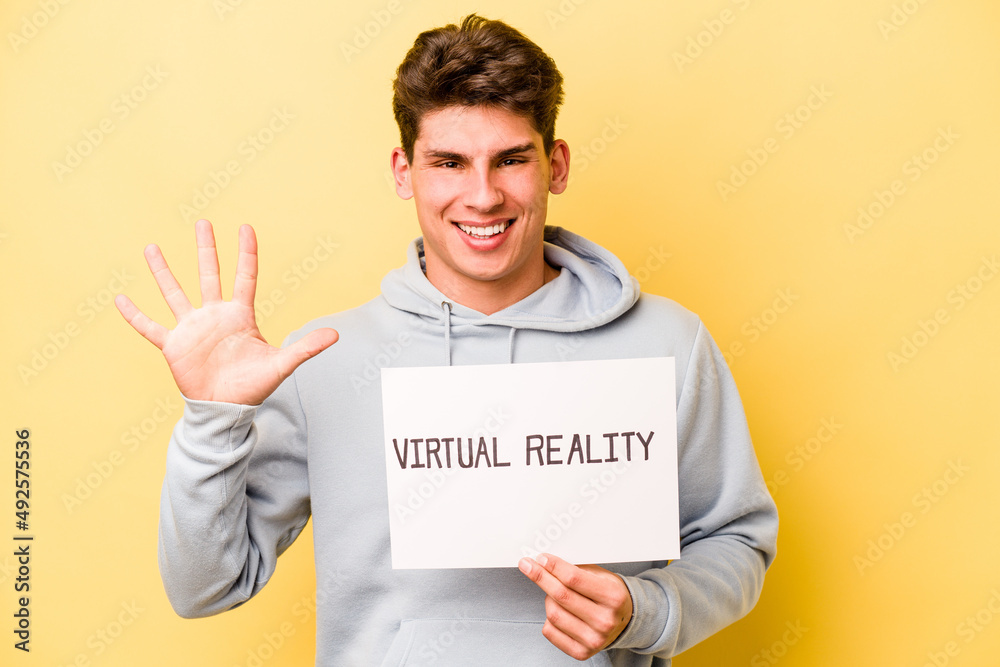 Young caucasian man holding virtual placard isolated on yellow background smiling cheerful showing number five with fingers. Young caucasian man holding virtual placard isolated on yellow background smiling cheerful showing number five with fingers.