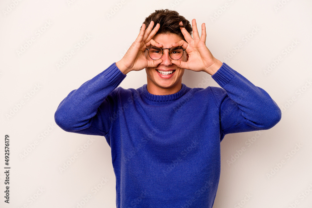 Young caucasian man isolated on white background showing okay sign over eyes Young caucasian man isolated on white background showing okay sign over eyes