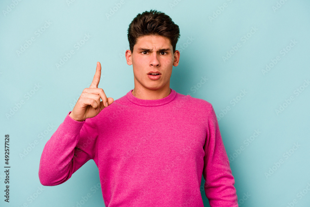 Young caucasian man isolated on blue background pointing upside with opened mouth. Young caucasian man isolated on blue background pointing upside with opened mouth.