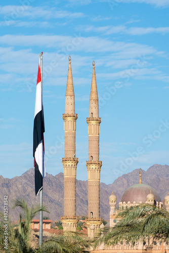 Sharm El Sheikh, Egypt - January 12, 2022: Al-Sahaba mosque in Sharm El Sheikh. Two minarets and egyptian flag on blue sky background. photo