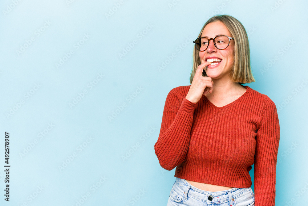 Young caucasian woman isolated on blue background relaxed thinking about something looking at a copy space. Young caucasian woman isolated on blue background relaxed thinking about something looking at a copy space.