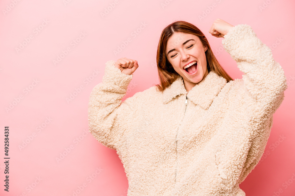 Young caucasian woman isolated on pink background raising fist after a victory, winner concept. Young caucasian woman isolated on pink background raising fist after a victory, winner concept.