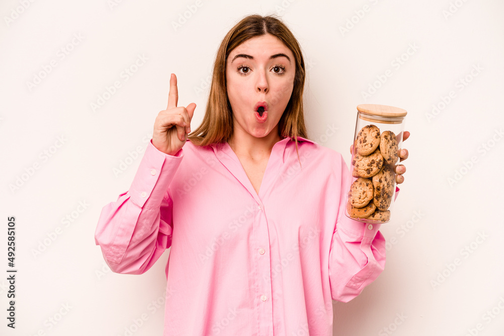 Young caucasian woman holding cookies jar isolated on white background having some great idea, concept of creativity. Young caucasian woman holding cookies jar isolated on white background having some great idea, concept of creativity.