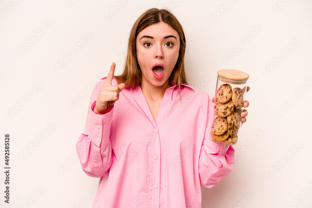 Young caucasian woman holding cookies jar isolated on white background having an idea, inspiration concept. Young caucasian woman holding cookies jar isolated on white background having an idea, inspiration concept.