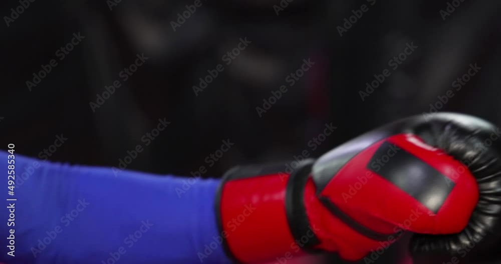 Close up boxing gloves hitting punching bag, training in boxing gym