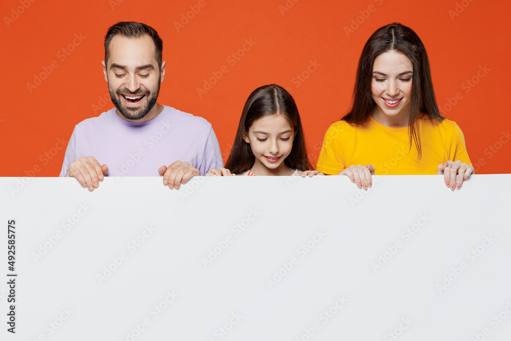 Young parents mom dad with child kid daughter teen girl wear basic t-shirts hold big white empty poster billboard for content, place for text or image isolated on yellow background Family day concept Young parents mom dad with child kid daughter teen girl wear basic t-shirts hold big white empty poster billboard for content, place for text or image isolated on yellow background Family day concept