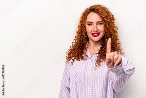 Young ginger caucasian woman isolated on white background showing number one with finger.